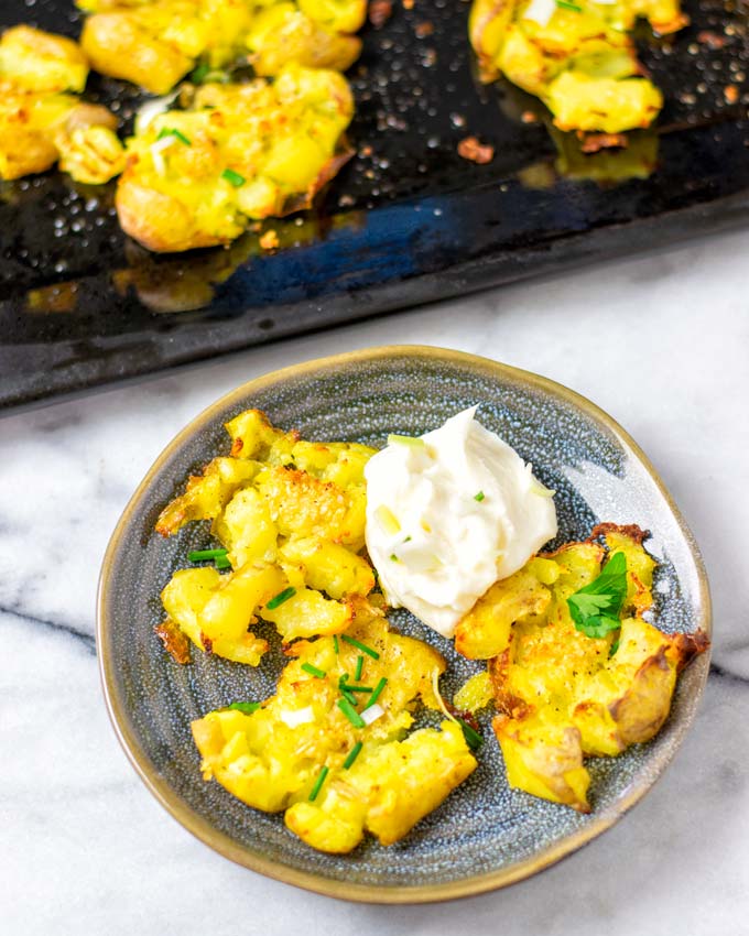 Portion of Smashed Potatoes on a small plate with the baking sheet in the background.