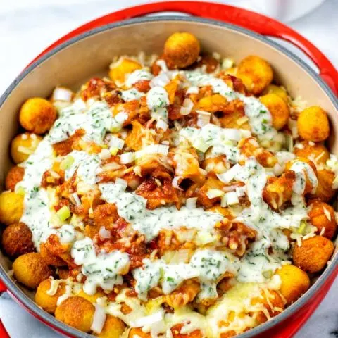 The casserole dish with the Totchos covered with Ranch Dressing.