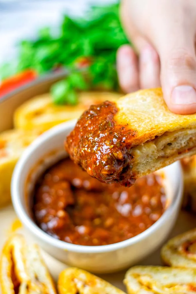 Showing the slice of Stromboli after dipping into tomato sauce.