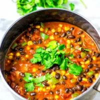 The Black Bean Chili is served in a large saucepan with some fresh cilantro on top.