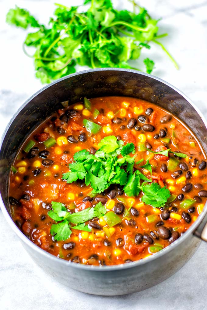 The Black Bean Chili is served in a large saucepan with some fresh cilantro on top.