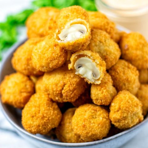 Large plate of Fried Mushrooms with one of them halved, revealing the inner juicy part.