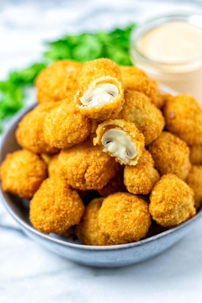 Large plate of Fried Mushrooms with one of them halved, revealing the inner juicy part.