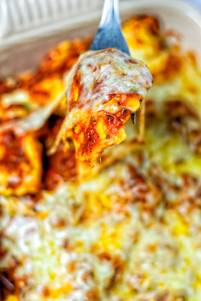 Closeup of a fork with a ravioli and melted vegan cheese.