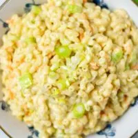 Top view on the Hawaiian Macaroni Salad in a large bowl, with creamy dressing, and the vegetable ingredients visible.