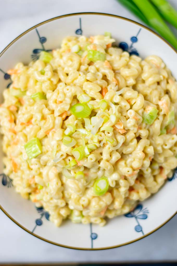 Top view on the Hawaiian Macaroni Salad in a large bowl, with creamy dressing, and the vegetable ingredients visible.