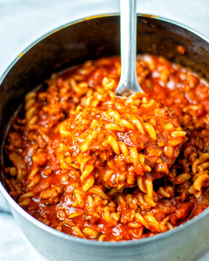 Closeup view of a large spoonful of the Lasagna Soup being lifted from the saucepan.