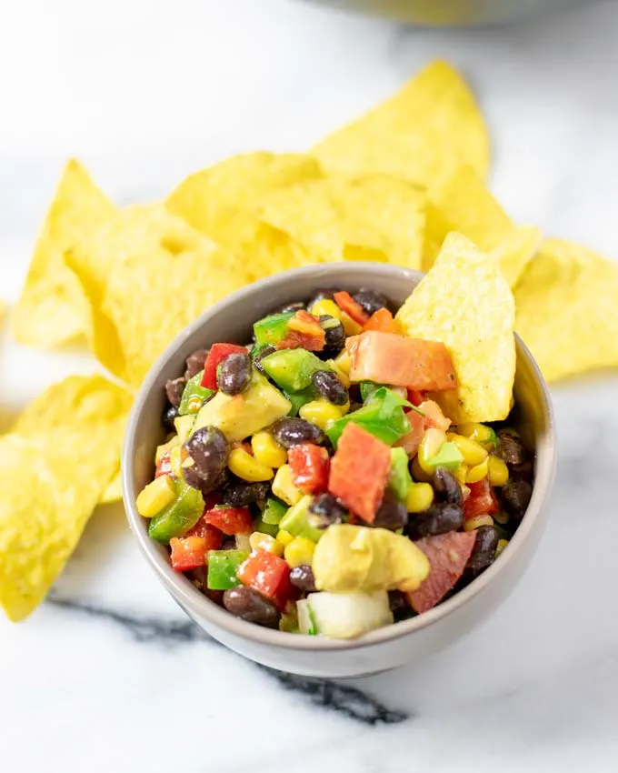 A portion of the Cowboy Caviar in a small bowl with tortilla chips.