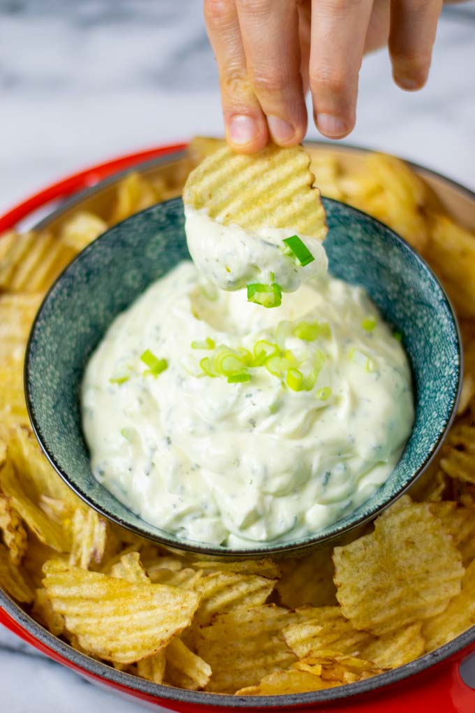 A potato chip is dipped into the dip.