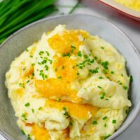 Large portion of the Creamy Potatoes on a grey plate, garnished with fresh chives.