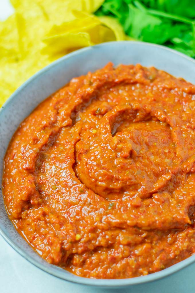 Ranchero Sauce in a serving bowl, with taco chips and fresh cilantro in the background.