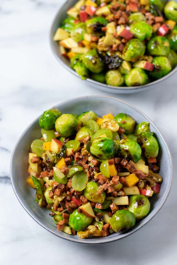 Two portions of the Brussels Sprouts Salad in grey bowls.