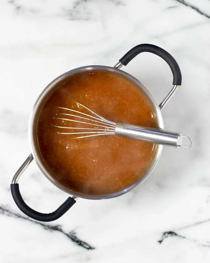 Showing the Hawaiian Sauce after cooking in a small saucepan with a wire whisk.