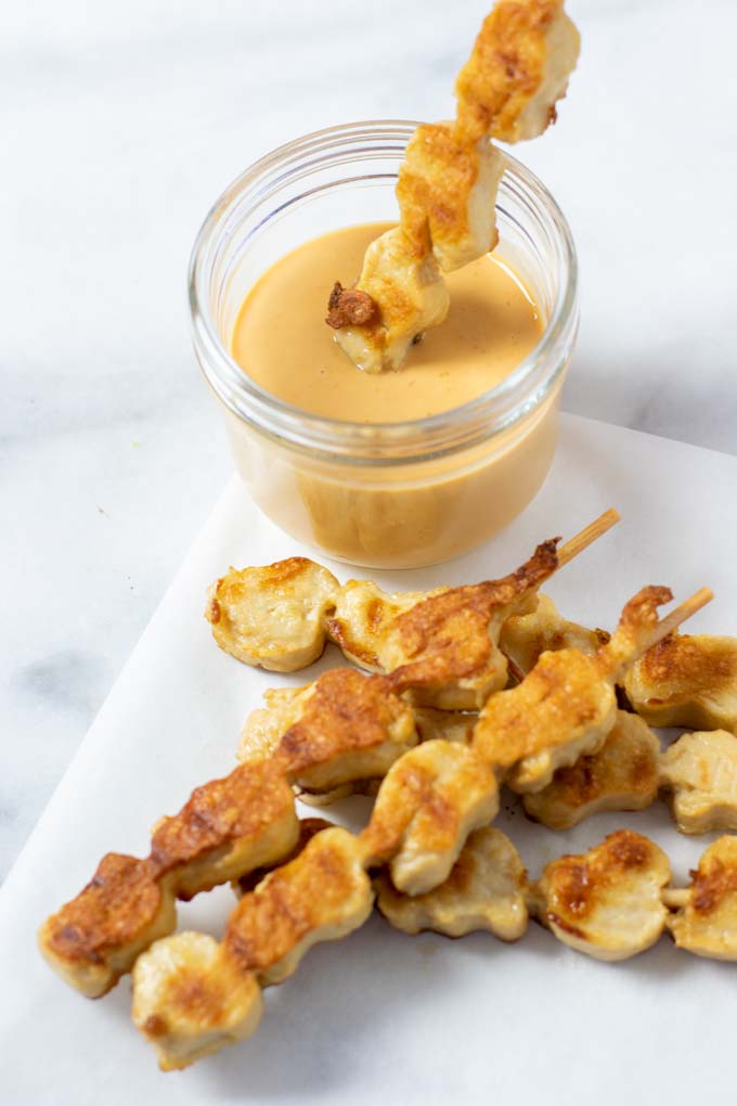 Vegan chicken sticks in front of a small jar with the Cane's Sauce.