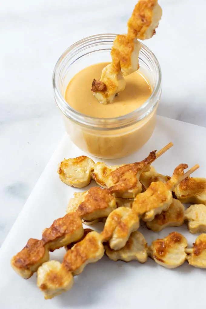 Vegan chicken sticks in front of a small jar with the Cane's Sauce.