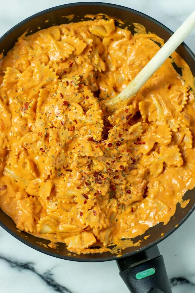 Top view of the Creamy Tomato Pasta in a pan, with a wooden spoon.