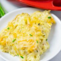 Closeup of a portion of the Hashbrown Potatoes on a white plate with the casserole dish in the background.