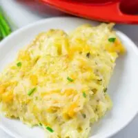 Closeup of a portion of the Hashbrown Potatoes on a white plate with the casserole dish in the background.