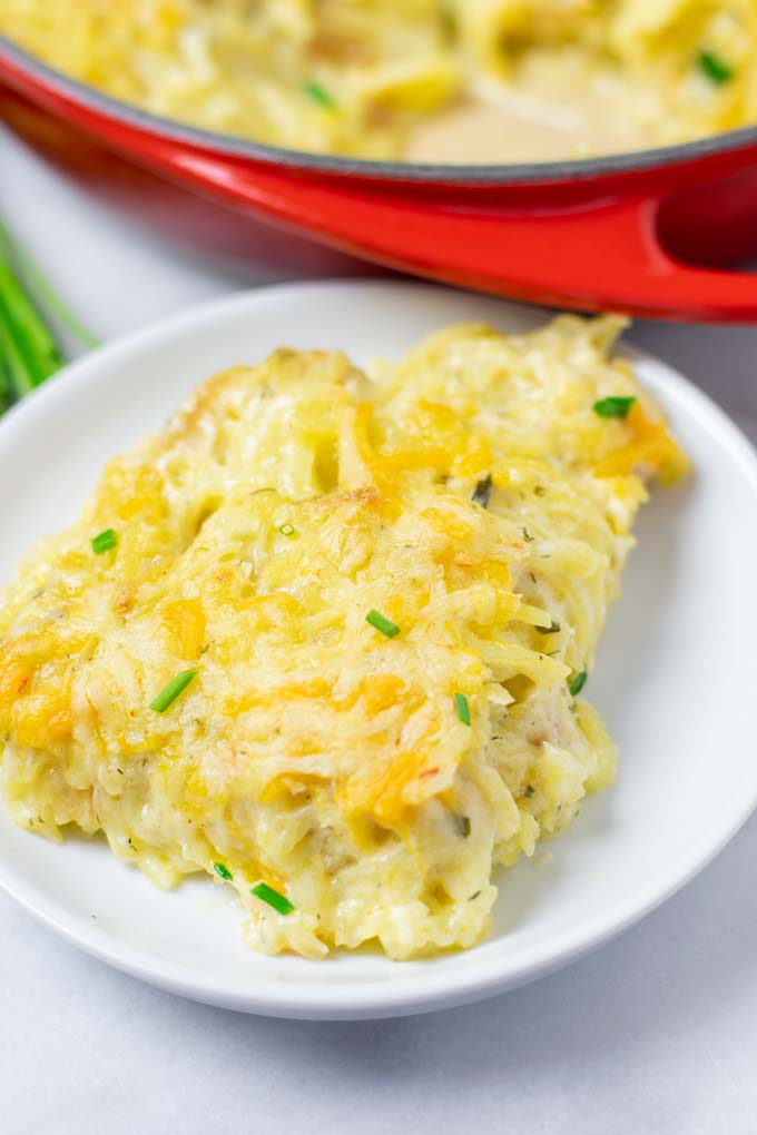 Closeup of a portion of the Hashbrown Potatoes on a white plate with the casserole dish in the background. 