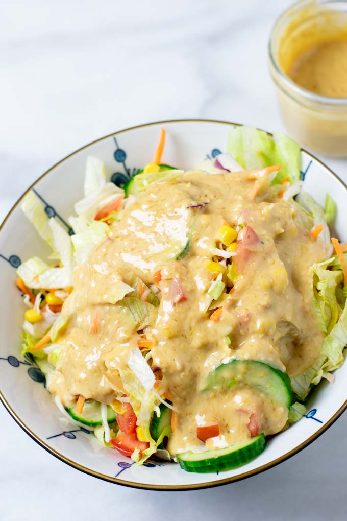 A large bowl of a mixed salad covered in the Roasted Sesame Dressing.