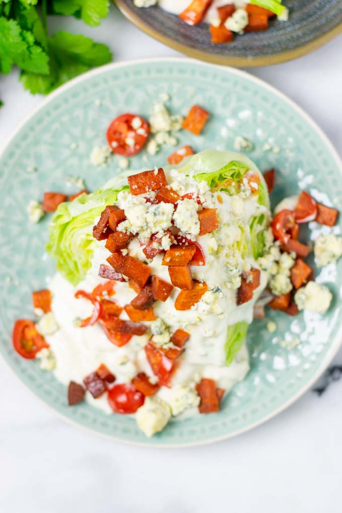 Top view of the Wedge Salad with extra bacon bites, tomatoes, and vegan blue cheese crumbles.