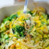 Closeup view of a large serving spoon full of the Broccoli Bake being lifted out of the casserole dish.