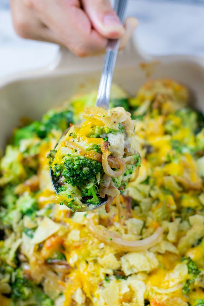 Closeup view of a large serving spoon full of the Broccoli Bake being lifted out of the casserole dish.