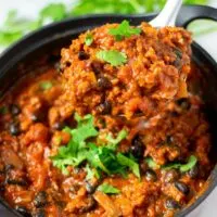 A large spoonful of Chipotle Chili is lifted out of the pot.