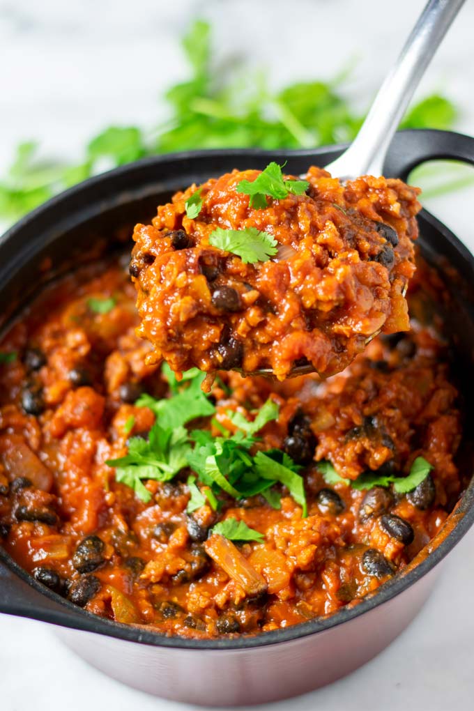 A large spoonful of Chipotle Chili is lifted out of the pot.