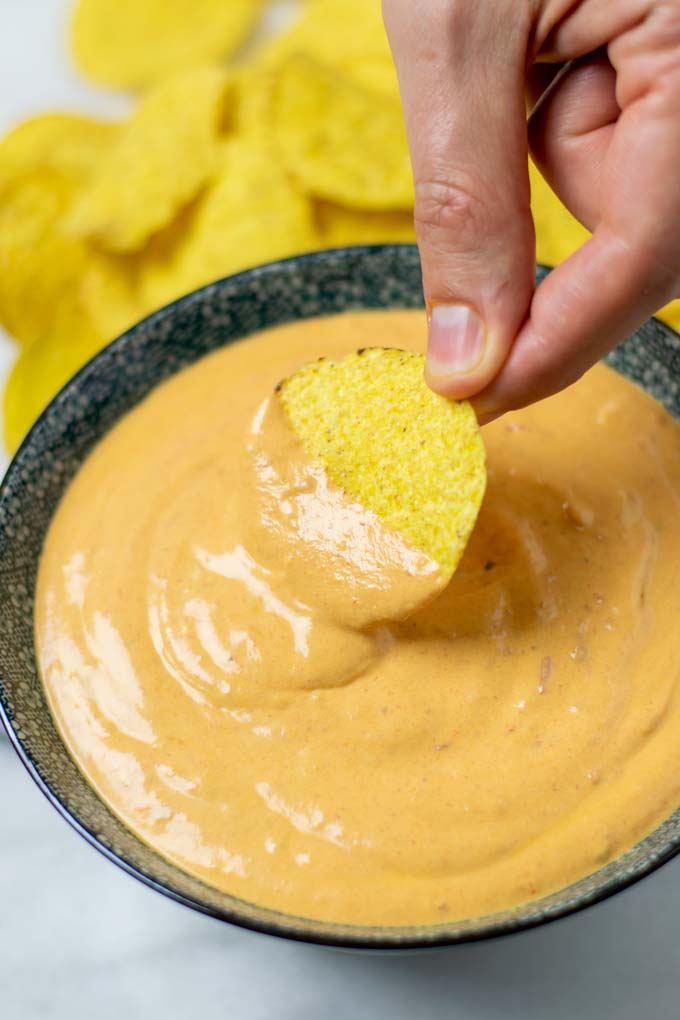 Dipping a tortilla chip into the sauce.