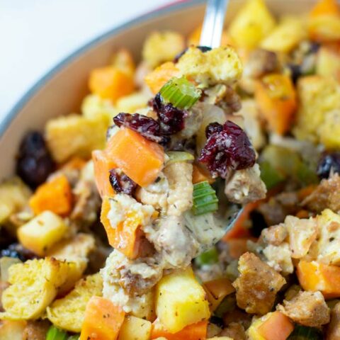 A large spoonful of of the Sweet Potato Stuffing is lifted from the casserole dish.