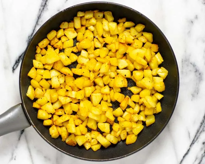 Top view of a frying man with the golden crispy Country Potatoes.