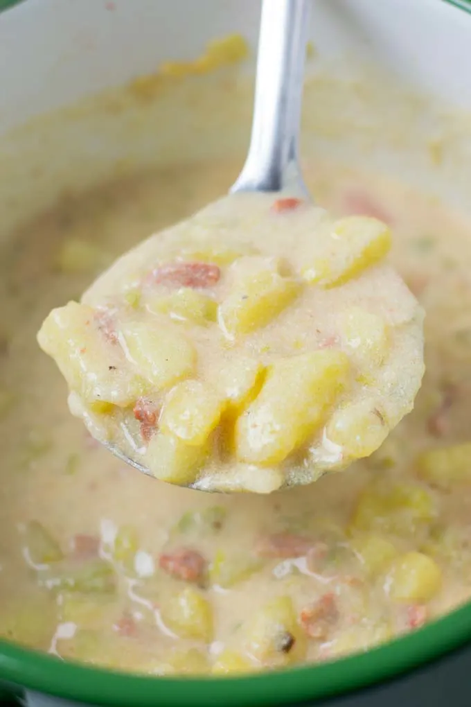 Closeup view of a large soup spoon full of the Creamy Potato Soup.