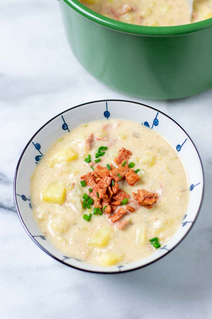 A portion of the Creamy Potato Soup in a small bowl, garnished with fried bacon and chives.