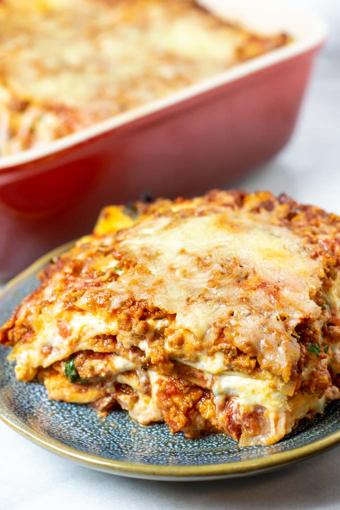 A large portion of the Easy Homemade Lasagna on a plate with the baking dish in the background.