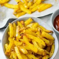 A serving of the Cajun Fries, with a side bowl of ketchup and the baking sheet in the background.