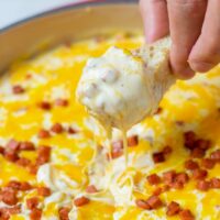 Showing how a piece of bread is dipped into the Hot Cheese Dip.