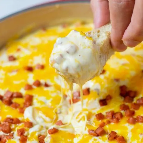 Showing how a piece of bread is dipped into the Hot Cheese Dip.