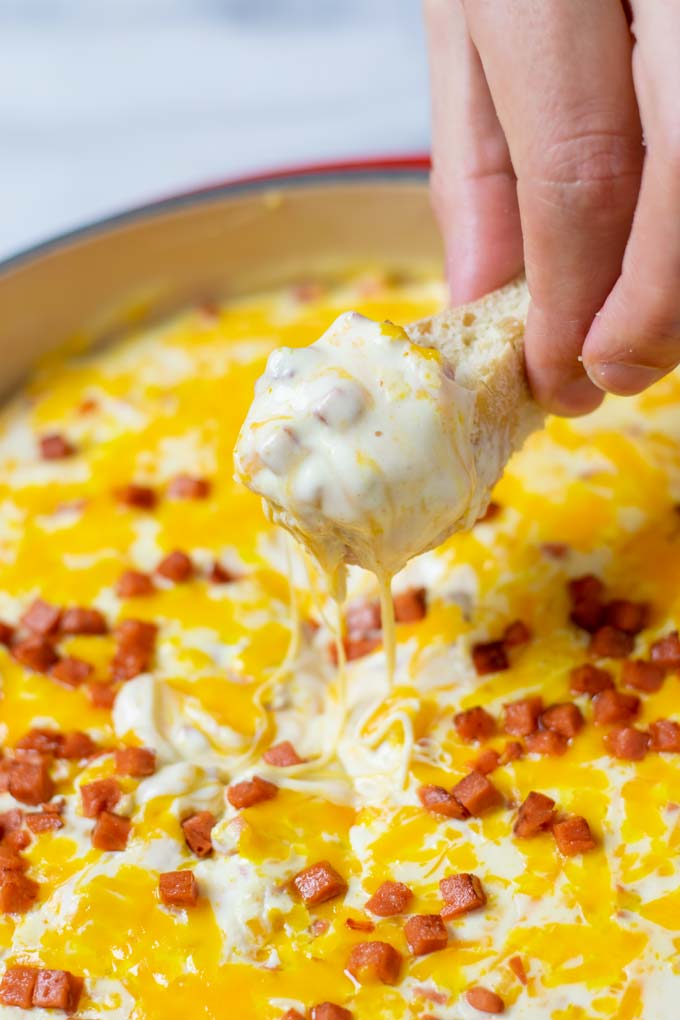 Showing how a piece of bread is dipped into the Hot Cheese Dip.