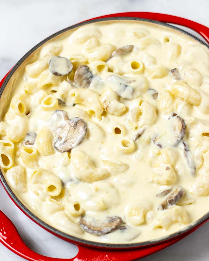 View of the ready Truffle Mac and Cheese in a red, round casserole dish.