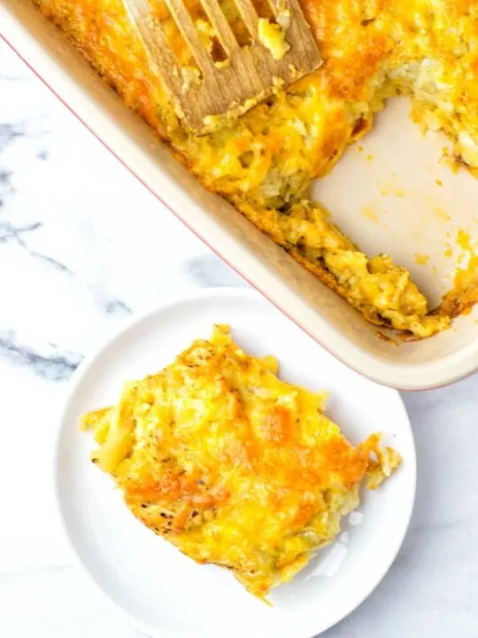 Top view on a plate with a portion of the Hashbrown Casserole, with the casserole baking dish in the background.