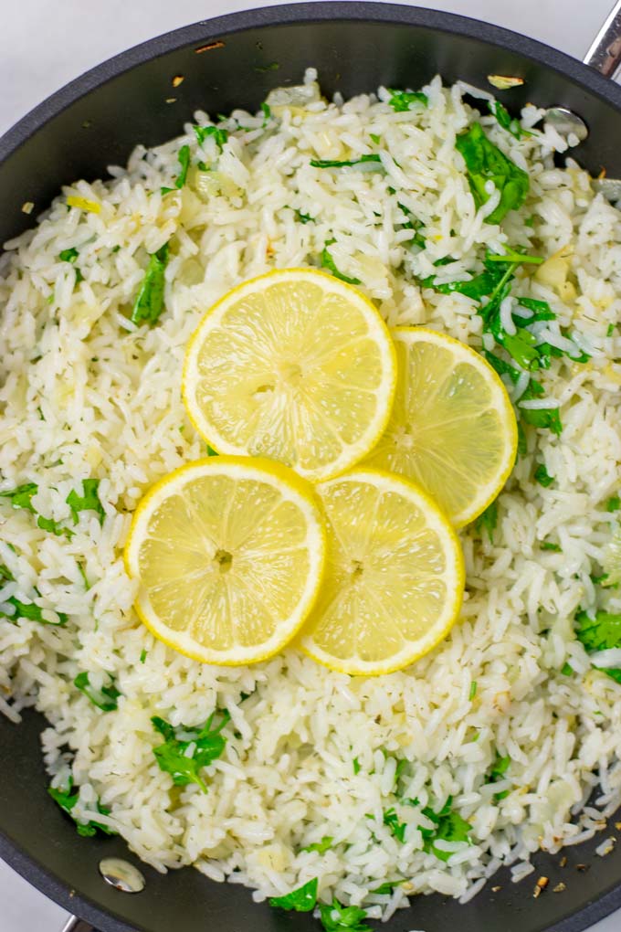 Top view on the Lemon Rice in a pan coming from the stove, garnished with thin lemon slices.