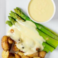 Top view of a plate of potatoes and asparagus with Mornay sauce.