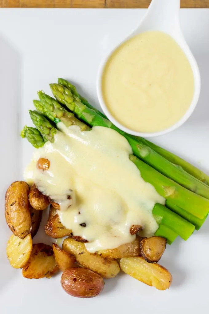 Top view of a plate of potatoes and asparagus with Mornay sauce.