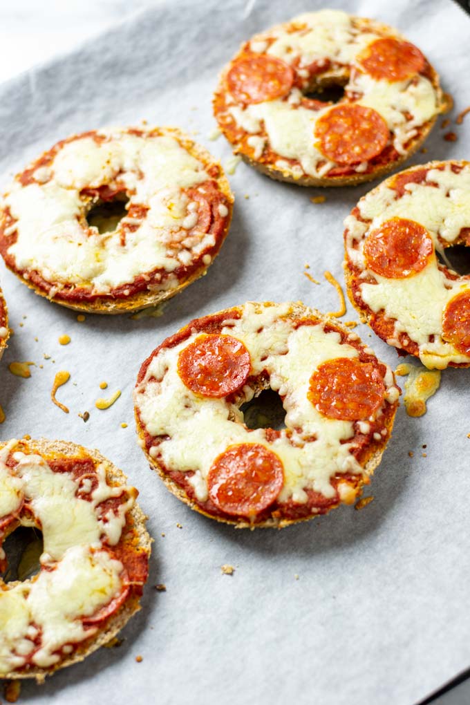 View of the freshly baked Pizza Bagels on a baking sheet, with different topping versions visible.