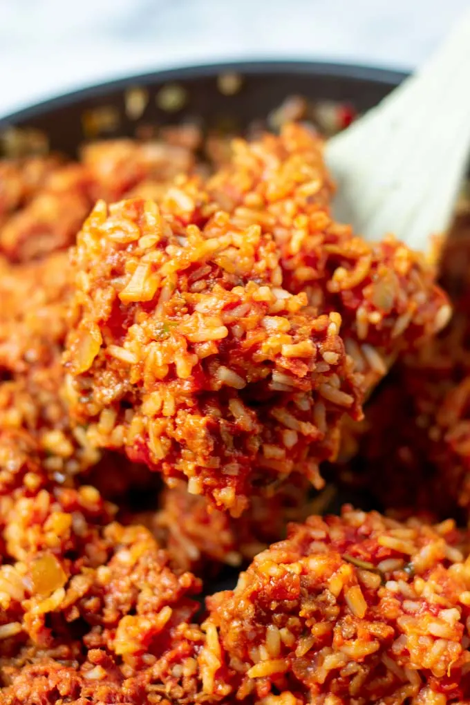 Closeup of a big portion of the Tomato Rice being lifted from the frying pan.