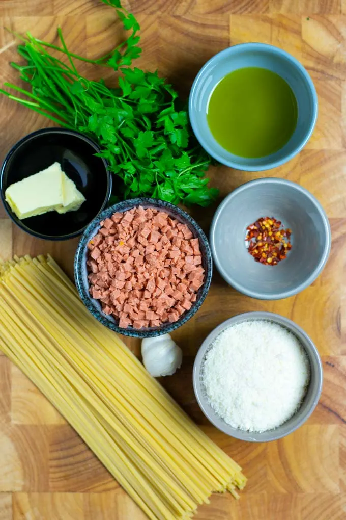 Ingredients needed to make this easy Bacon Pasta are assembled on a wooden board.