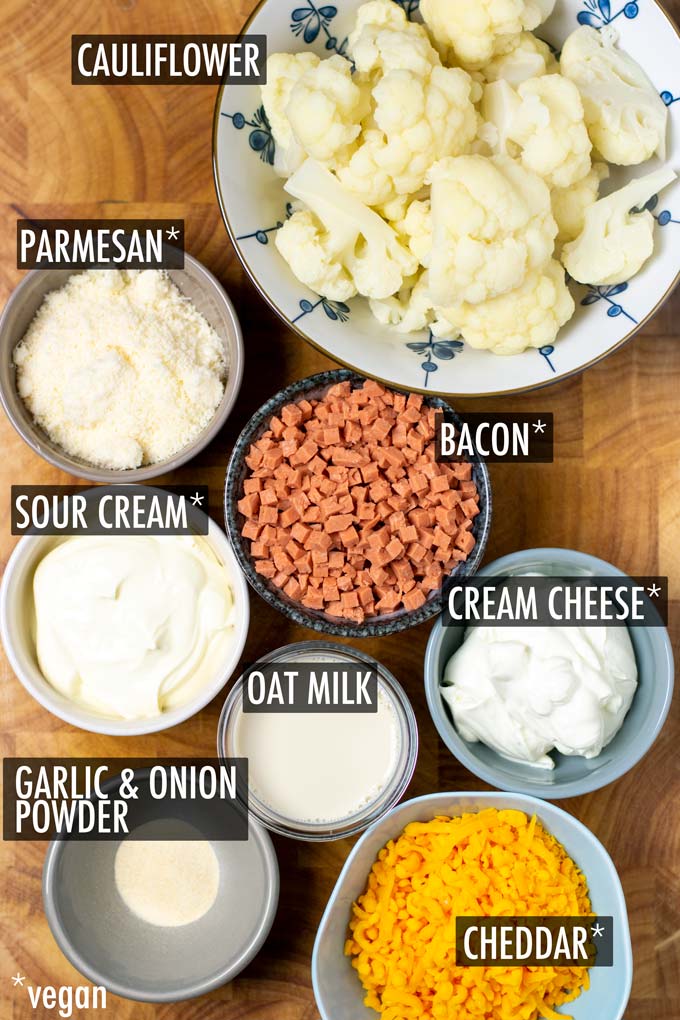 Ingredients needed for this Cauliflower Bake recipe are arranged on a wooden board and labeled. 