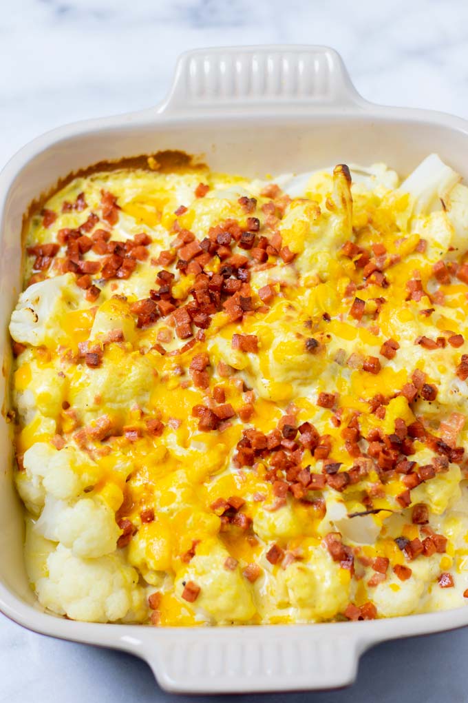 The ready Cauliflower Bake as taken from the oven, showing the cauliflower in the sauce with a baked crust of vegan cheddar and extra bacon.