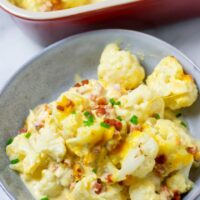 A large portion of the Cauliflower Bake on a plate with the casserole dish visible in the background.